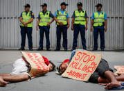 <p>Filipino demonstrators (foreground) mimic an extrajudicial killing crime scene as police officers stand guard during a protest in front of the Philippine National Police (PNP) headquarters in Camp Crame, Quezon City, northeast of Manila, Philippines, Aug. 26, 2016. (Photo: MARK R. CRISTINO/EPA) </p>