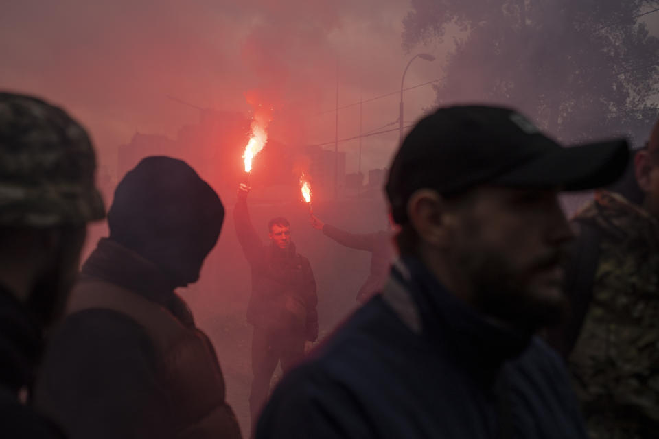 Friends light torches at the burial of Ukrainian soldier Oleksandr Hrianyk in Kyiv, Ukraine, Saturday, Oct. 28, 2023. Hrianyk died in battle in May 2022 in the city of Mariupol, but was only cremated recently after his remains were found and identified. (AP Photo/Bram Janssen)