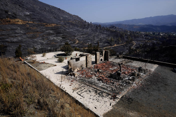 A burnt house is seen on outskirts of Ora village, in the background is the Larnaca mountain region, Cyprus, Sunday, July 4, 2021. Cyprus' interior minister says four people have died in what he called the “most destructive" fire in the island nation's history. (AP Photo/Petros Karadjias)