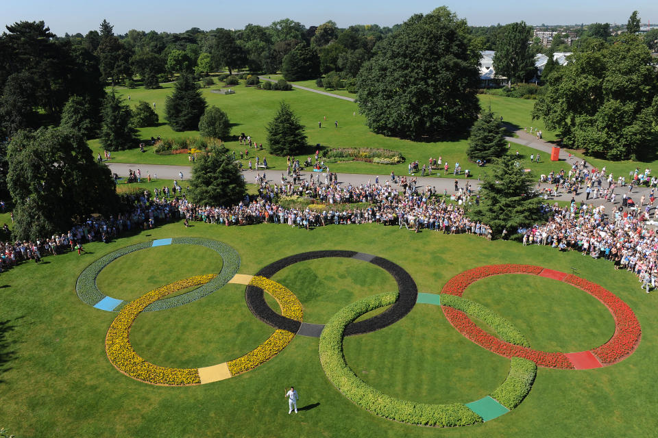 In this handout image provided by LOCOG, Torchbearer 048 Oliver Golding holds the Olympic Flame in between the Olympic Rings at Kew Gardens on July 24, 2012 in London, England. The Olympic Flame is now on Day 67 of a 70-day relay involving 8,000 torchbearers covering 8,000 miles. (Photo by LOCOG via Getty Images)