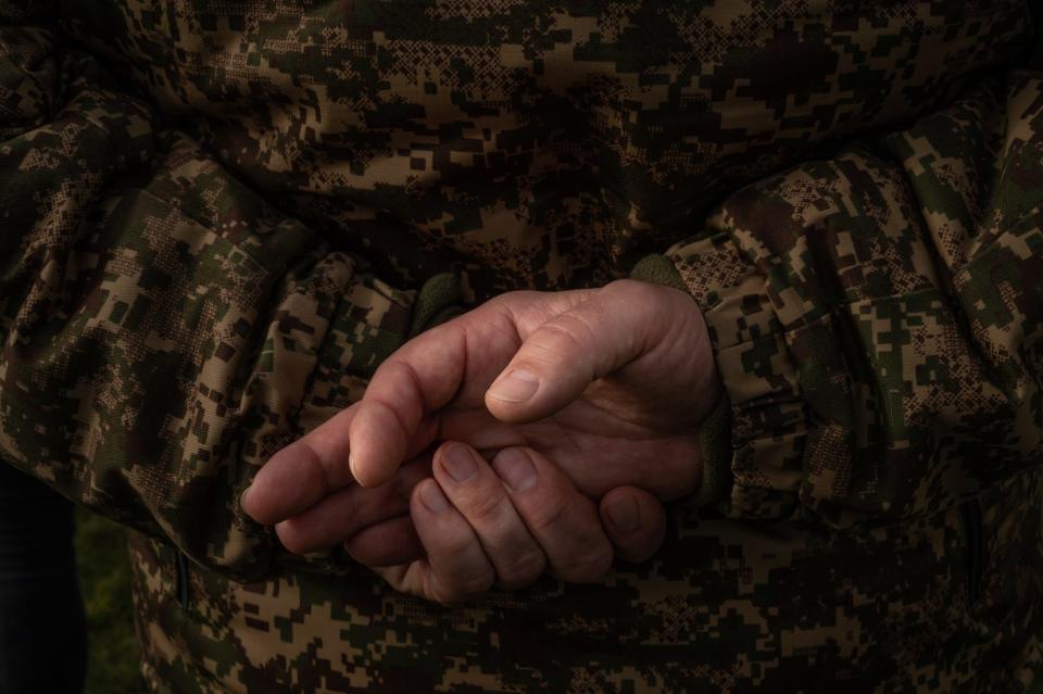 A close up image of a Ukrainian soldiers' hands held together behind his back