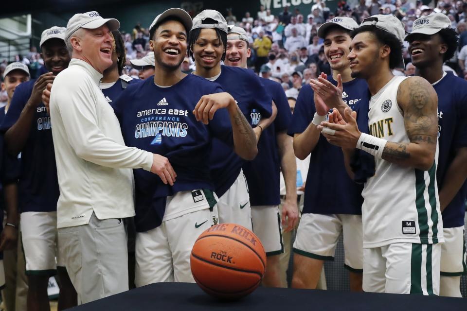 Vermont head coach John Becker, left, celebrates with his team after defeating UMass Lowell in the NCAA college basketball game in the final of the America East Conference Tournament, Saturday, March 11, 2023, in Burlington, Vt. (AP Photo/Michael Dwyer)