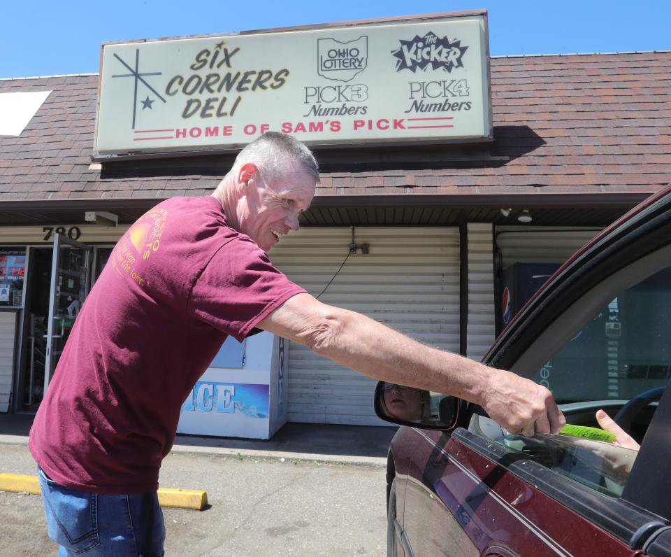 Wayne Parsil, a member of the Akron Restoration Home, hands an informational sheet to a donor at the Six Corners Deli in Akron.