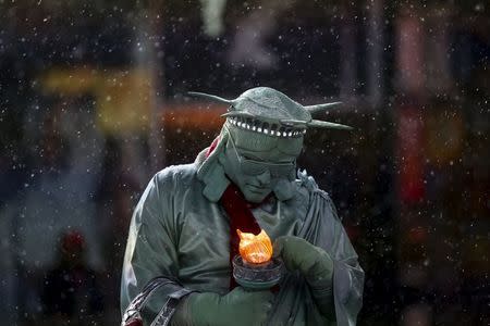 A man dressed as the "Statue of Liberty" tries to fix his light as it begins to snow in Times Square in the Manhattan borough of New York, January 22, 2016. REUTERS/Carlo Allegri