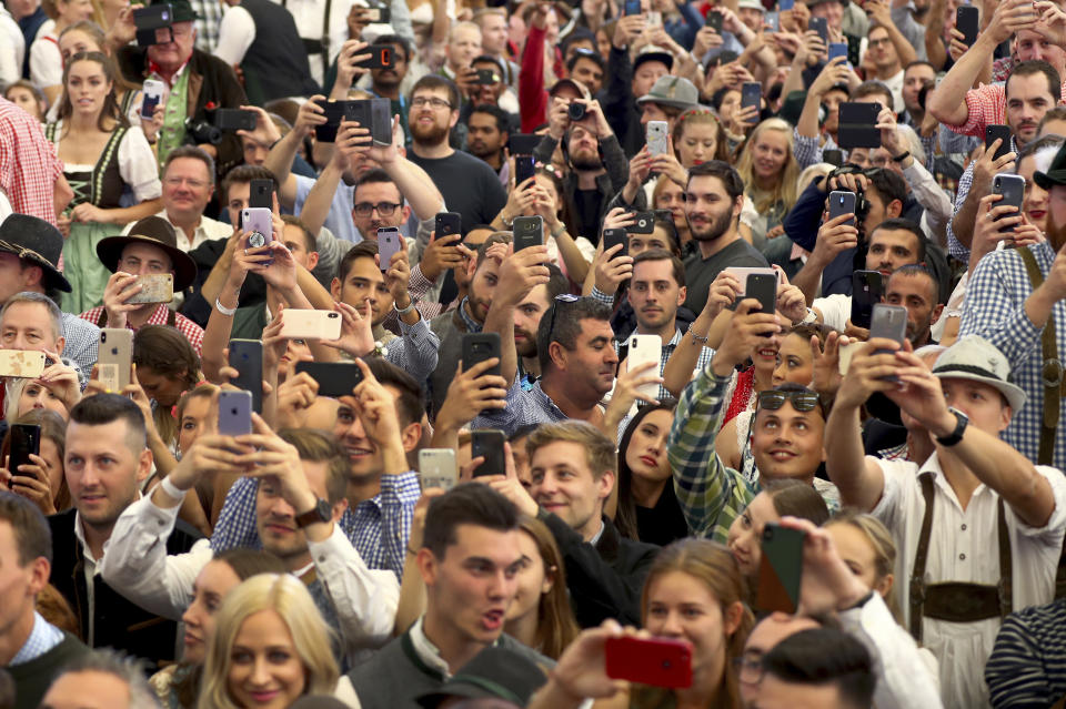 Visitors hold smartphones during the opening of the 186th 'Oktoberfest' beer festival in Munich, Germany, Saturday, Sept. 21, 2019. (AP Photo/Matthias Schrader)