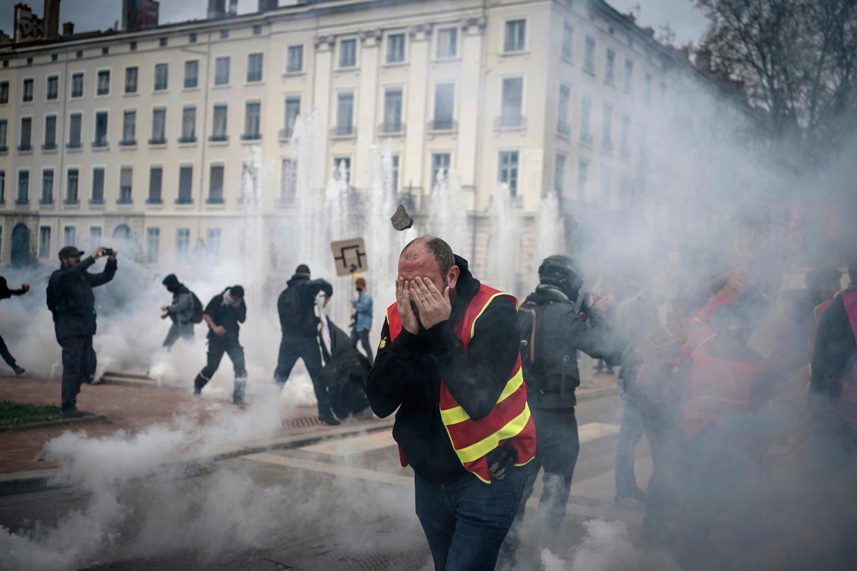 Protesters run in tear gas during a demonstration in Lyon, central France (AP)