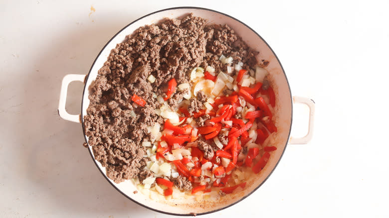 Ground beef, onions, and roasted red peppers in Dutch oven