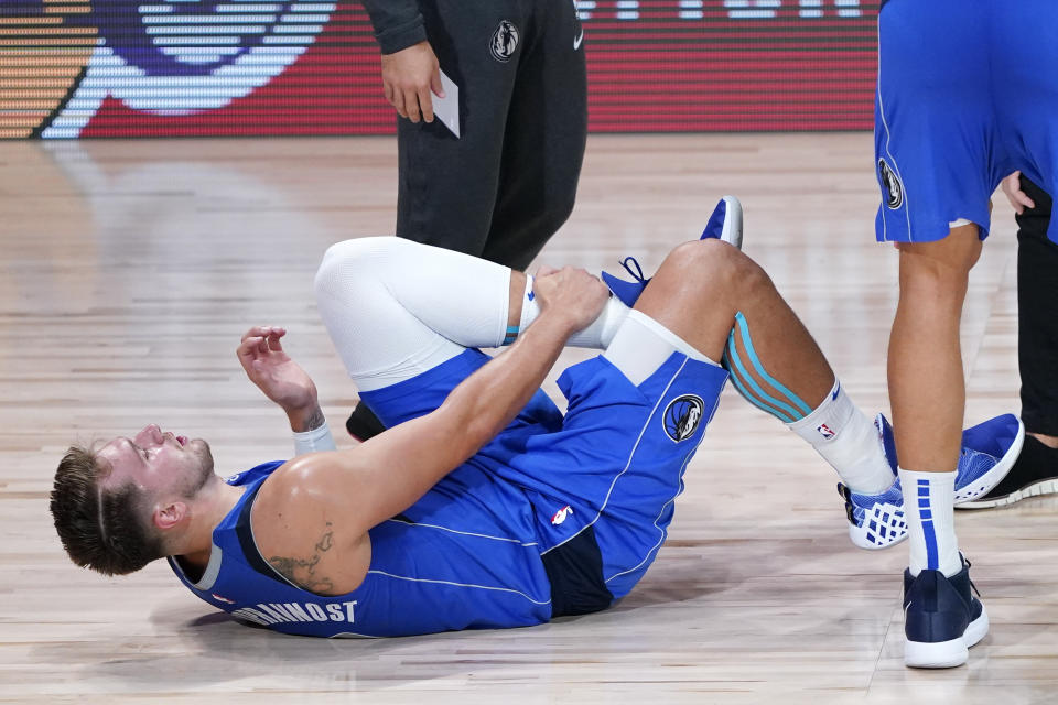 Dallas Mavericks' Luka Doncic (77) grabs his left leg after being injured during the second half of an NBA basketball first round playoff game against the Los Angeles Clippers Friday, Aug. 21, 2020, in Lake Buena Vista, Fla. (AP Photo/Ashley Landis, Pool)