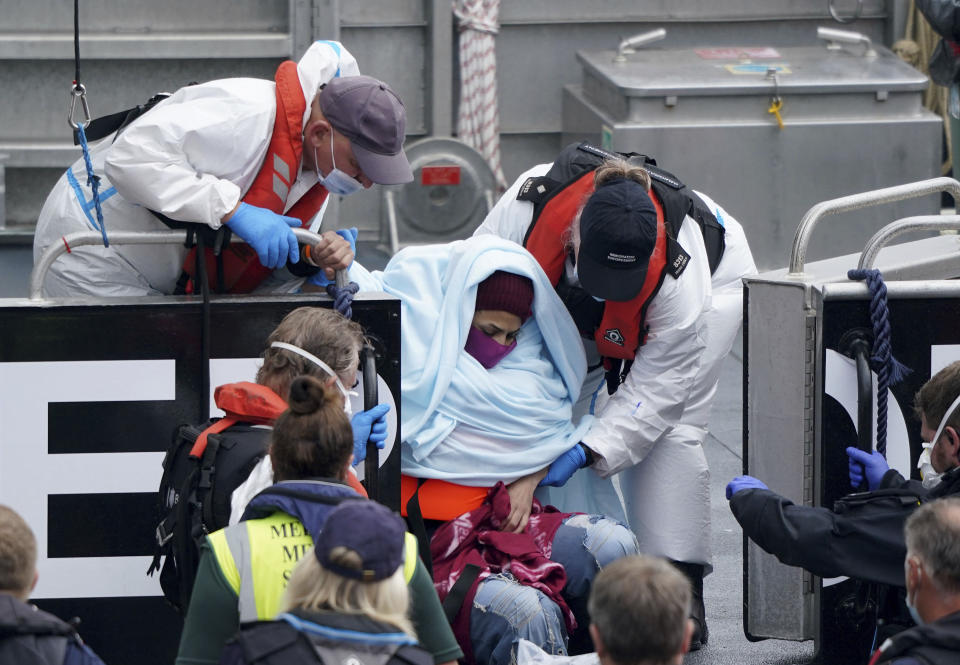 A woman is helped by Border Force officers as a group of people thought to be migrants are brought in to Dover, onboard a Border Force vessel, following a small boat incident in the Channel, in Kent, England, Monday July 26, 2021. (Gareth Fuller/PA via AP)