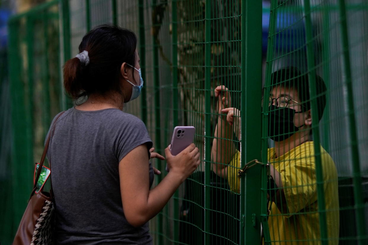 People chat through gaps in a barrier at a sealed area, amid new lockdown measures in parts of the city to curb the coronavirus disease (COVID-19) outbreak in Shanghai, China June 16, 2022. REUTERS/Aly Song