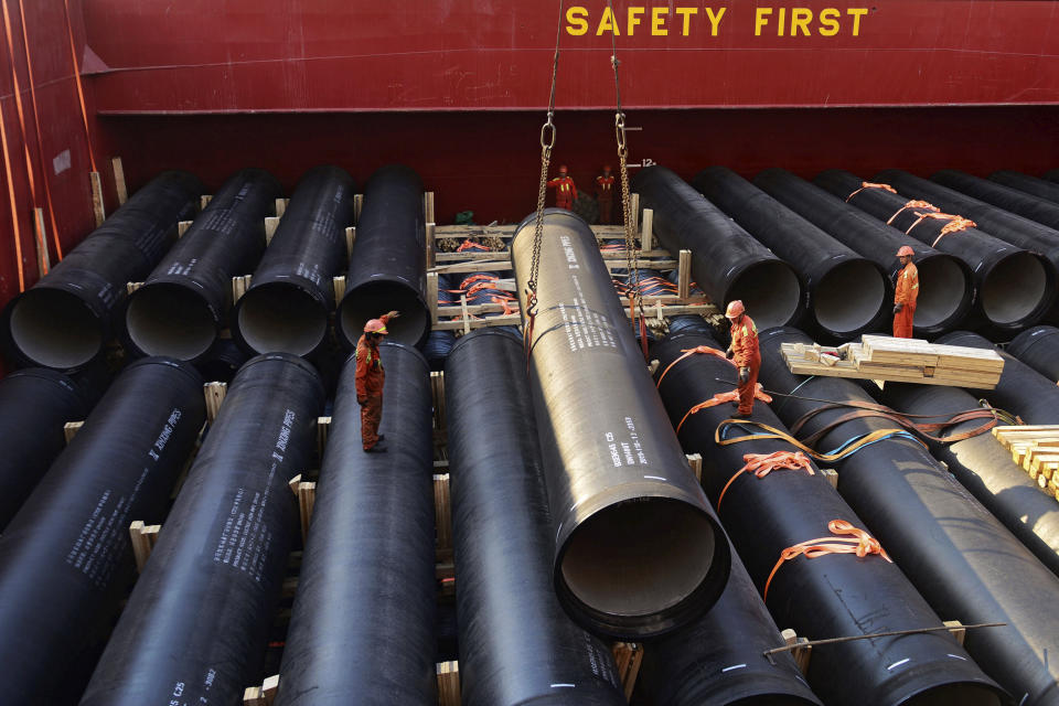 In this Monday, April 1, 2019, photo, workers load cylinders on a container vessel at a port in Qingdao in east China's Shandong province. Trade tensions between China and the United States are putting a drag on economies in the region, with growth likely to continue to slow in the coming two years, the Asian Development Bank says in a report released Wednesday, April 3, 2019. (AP Photo)