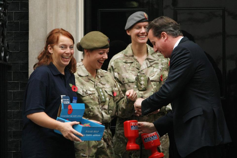 LONDON, ENGLAND - OCTOBER 25: British Prime Minister David Cameron makes a donation to receive a poppy from the Royal British Legion on the steps of Number 10 Downing Street during a photocall on October 25, 2012 in London, England. The annual Royal British Legion Poppy Appeal raises money to support members of the armed forces. at 10 Downing Street on October 25, 2012 in London, England. (Photo by Jordan Mansfield/Getty Images)