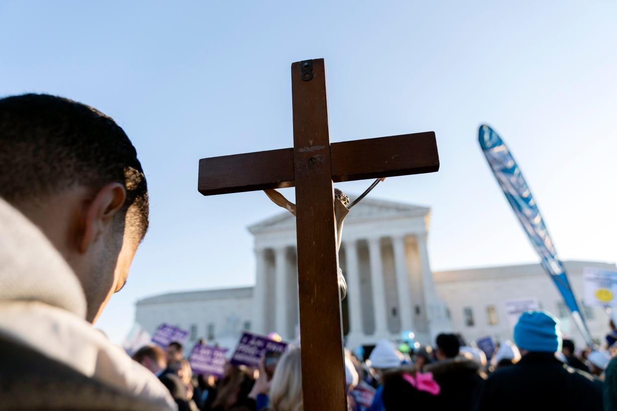 An abortion protester holds a cross outside the U.S. Supreme Court on Dec. 1 as justices consider state restrictions on the procedure.