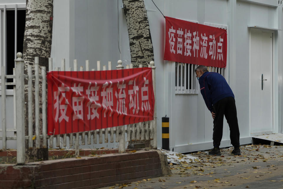 A man wearing a face mask peeps inside a COVID-19 vaccination mobile facility in Beijing, Wednesday, Oct. 26, 2022. The Chinese city of Shanghai started administering an inhalable COVID-19 vaccine on Wednesday in what appears to be a world first. (AP Photo/Andy Wong)