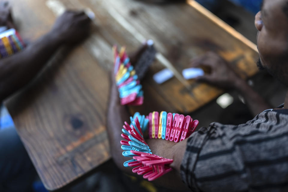 Un jugador de dominó con pinzas en el brazo colocadas cada vez que pierde en una escuela pública que sirve de refugio a personas desplazadas de sus hogares por los enfrentamientos entre pandillas en Puerto Príncipe, Haití, el lunes 22 de abril de 2024. Hace mucho que el sistema de salud de Haití era frágil, pero ahora se acerca al colapso total después de que las pandillas lanzaran ataques coordinados el 29 de febrero contra infraestructura crítica en la capital y otros lugares. (AP Foto/Ramón Espinosa)