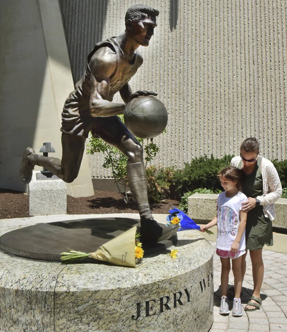 Visitors leave flowers at the base of a statue of West Virginia's Jerry West, Wednesday, June 12, 2024, outside the WVU Coliseum in Morgantown, W.Va. West, who was selected to the Basketball Hall of Fame three times in a storied career as a player and executive, and whose silhouette is considered to be the basis of the NBA logo, died Wednesday morning. He was 86. (Ron Rittenhouse/The Dominion-Post via AP)