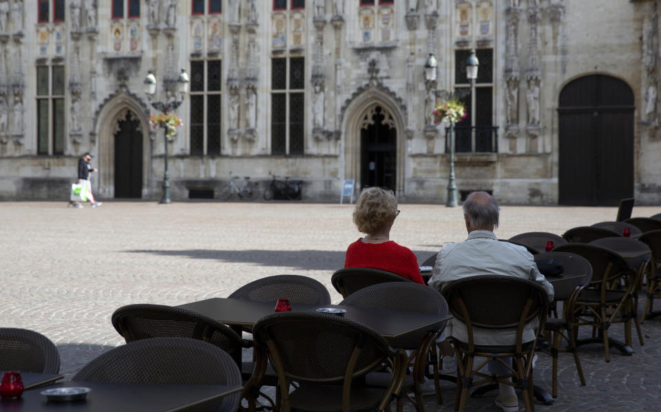 An older couple sit in an empty terrace of a restaurant in a historic square of Bruges, Belgium, Monday, Aug. 24, 2020. Tourism sector losses have piled up in the tens of billions of euros across the 27-nation European Union, and the continent's vaunted government support and social security system is under increasing strain to prop up the sector. (AP Photo/Virginia Mayo)