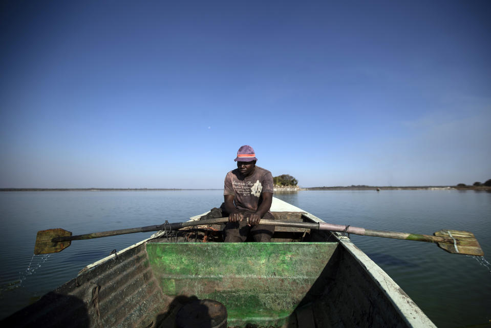 A fisherman rows his boat after casting his nets for the night, in Lake Chivero, west of the capital Harare, in Zimbabwe Tuesday, Sept. 10, 2019. Former president Robert Mugabe, who enjoyed strong backing from Zimbabwe's people after taking over in 1980 but whose support waned following decades of repression, economic mismanagement and allegations of election-rigging, is expected to be buried on Sunday, state media reported. (AP Photo/Ben Curtis)
