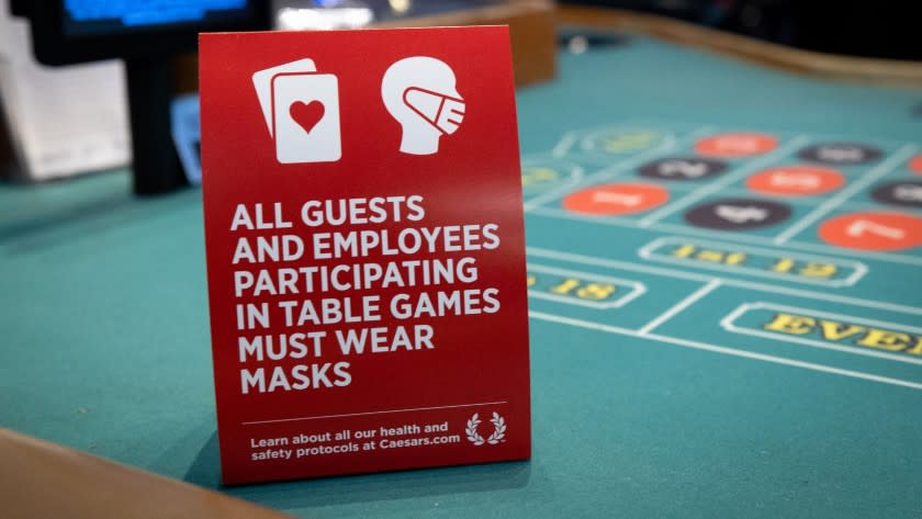 A sign on a gaming table in Paris Las Vegas reminds visitors that they need to cover their faces. A statewide mask order will go into effect Friday. <span class="copyright">(Caesars Entertainment)</span>