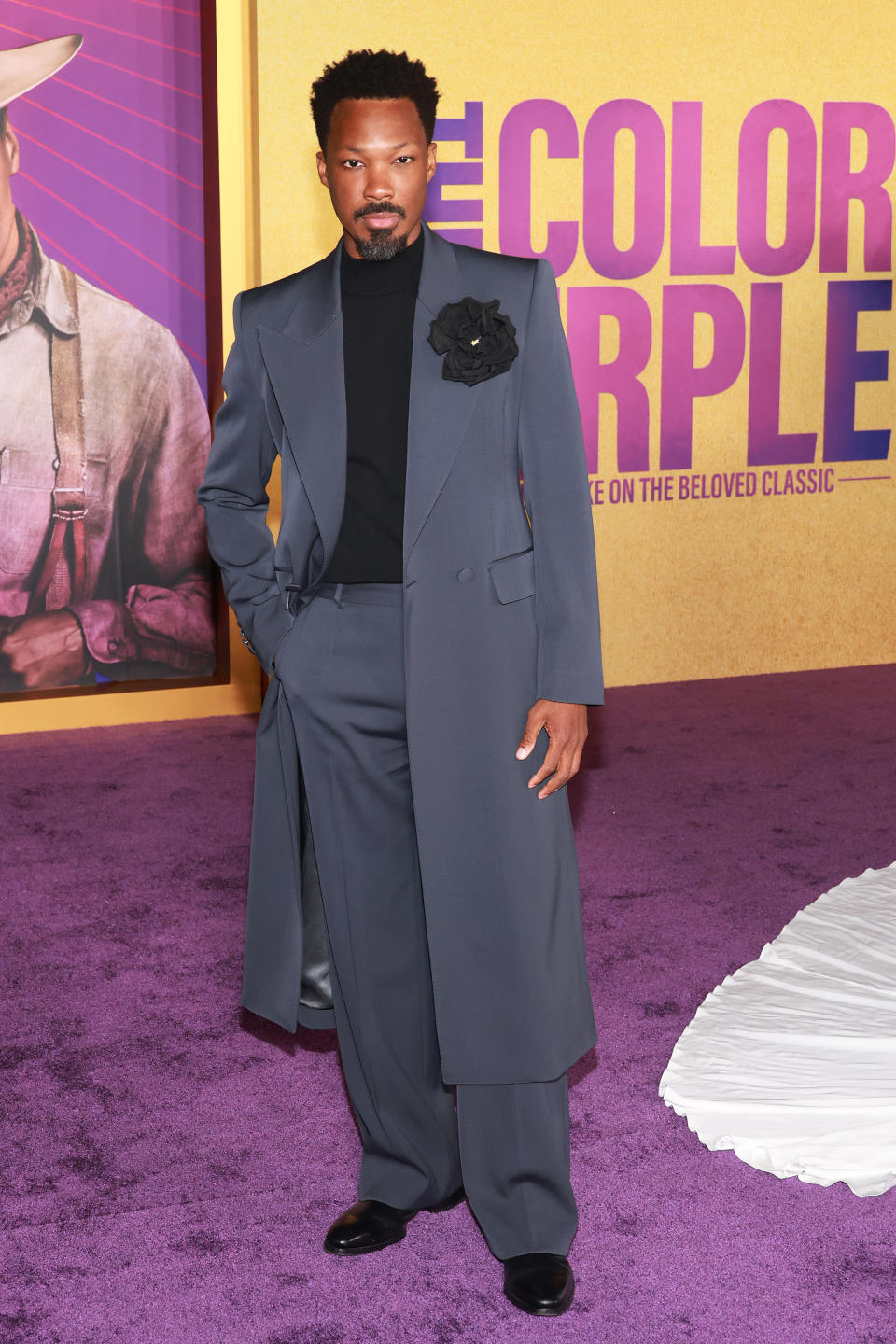 Close-up of Corey in a gray suit with mid-calf jacket, black shirt, and black corsage