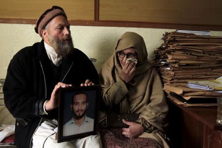 Muhammad Azeem (L) and Sajida Parveen, the parents of Ehsan Azeem, who was sentenced to death by a military court, react while holding their son's picture during an interview with Reuters in Rawalpindi January 23, 2015. REUTERS/Faisal Mahmood