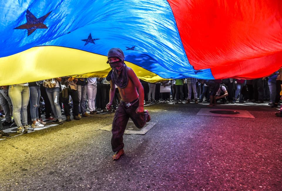A boy runs under a Venezuelan flag during a protest o June 27 against attacks on journalists.