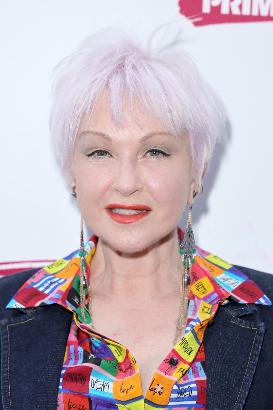 Cyndi Lauper aux cheveux courts portant un chemisier coloré et une veste en jean