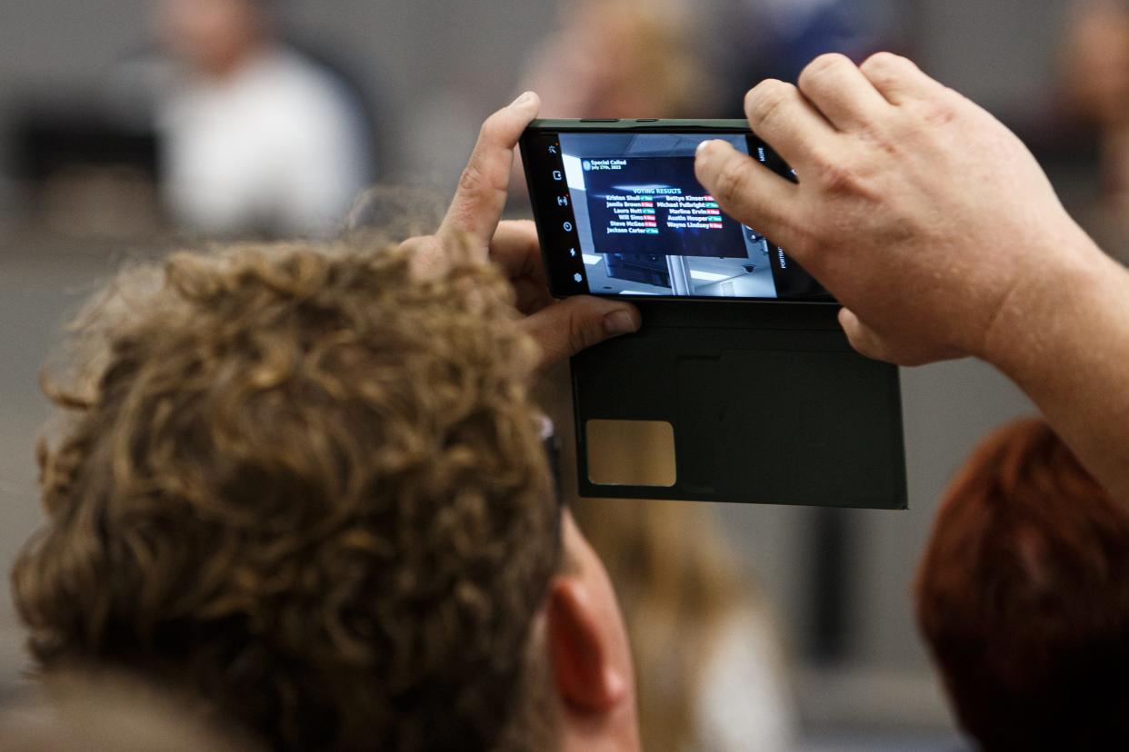 A man takes a photo of a vote denying American Classical Education during a Maury County Public Schools special hearing in Columbia, Tenn. on Thursday, July 27, 2023