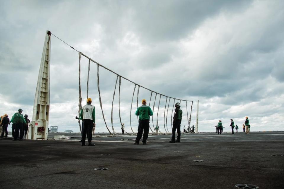 Sailors raise the crash barrier during a training exercise on the flight deck of Nimitz-class aircraft carrier USS George Washington (CVN 73).