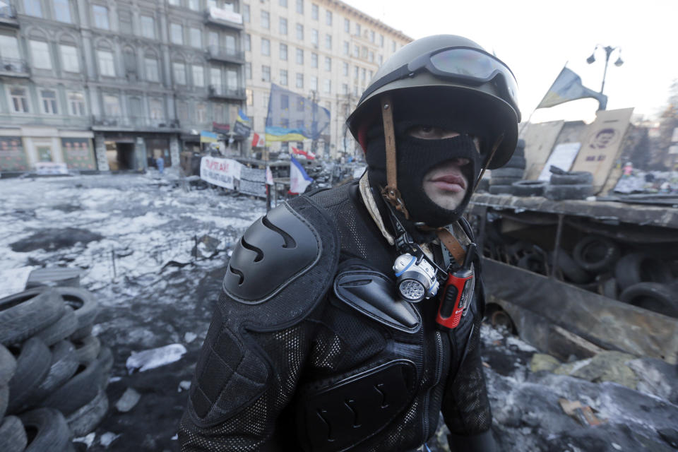 An opposition supporter guards a barricade outside Kiev's Independence Square, the epicenter of the country's current unrest, Ukraine, Sunday, Feb. 2, 2014. Kitted out in masks, helmets and protective gear on the arms and legs, radical activists are the wild card of the Ukraine protests now starting their third month, declaring they're ready to resume violence if the stalemate persists.(AP Photo/Efrem Lukatsky)