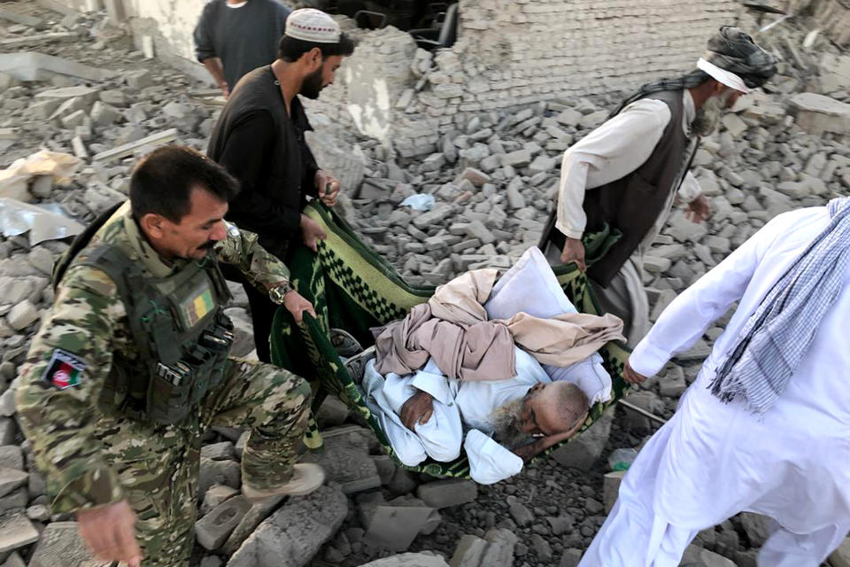 An Afghan security member and people carry an injured man after a suicide attack in Zabul, Afghanistan, Thursday, Sept. 19, 2019. A powerful early morning suicide truck bomb devastated a hospital in southern Afghanistan on Thursday. (AP Photo/Ahmad Wali Sarhadi)