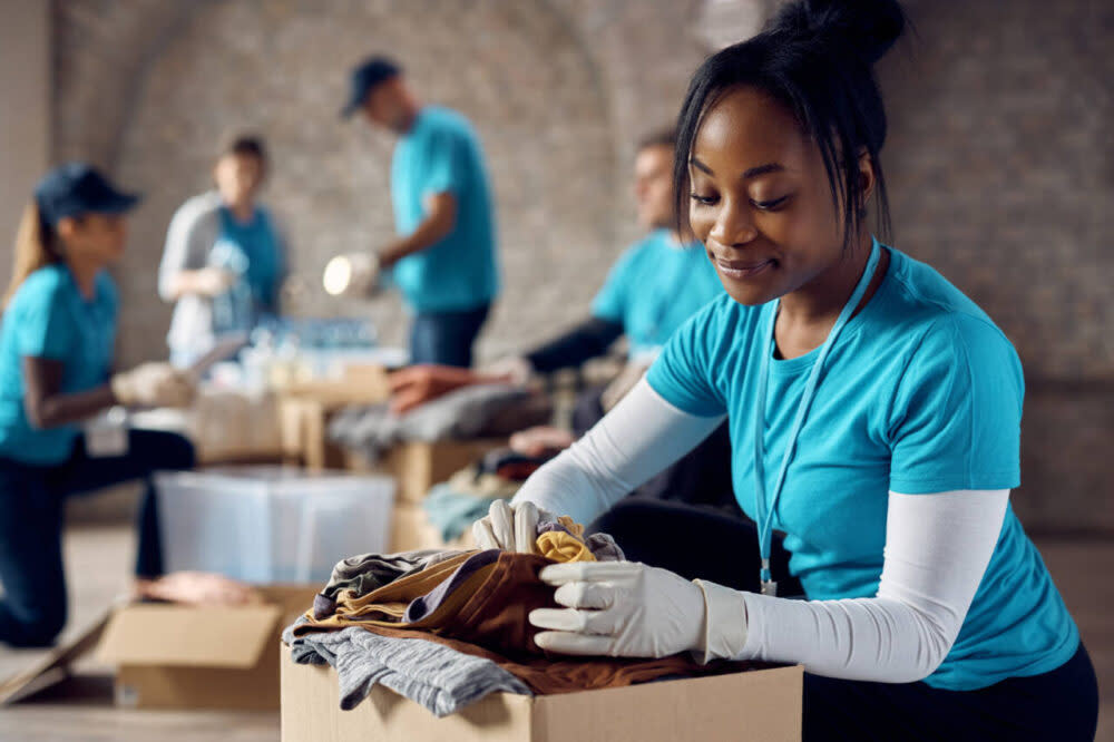 A young woman organizes clothing donations in a box