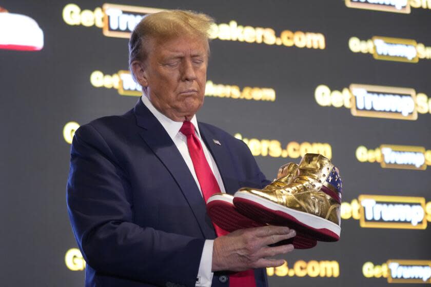 Republican presidential candidate former President Donald Trump holds gold Trump sneakers at Sneaker Con Philadelphia, an event popular among sneaker collectors, in Philadelphia, Saturday, Feb. 17, 2024. (AP Photo/Manuel Balce Ceneta)