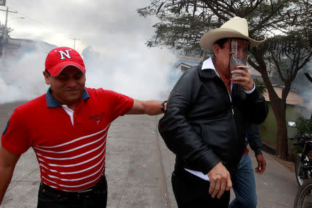 Honduras' former President Manuel Zelaya (R), covers his face from tear gas during a protest against the re-election of Honduras' President Juan Orlando Hernandez in Tegucigalpa, Honduras January 20, 2018. REUTERS/Jorge Cabrera