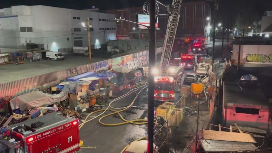 A homeless encampment is seen as firefighters battle a fire near an overpass in downtown Los Angeles on Nov. 11, 2023. (KTLA)