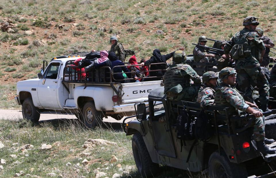 Lebanese citizens who fled their houses from the Lebanese-Syrian border village of Tfail, sit on a pickup as they pass next of Lebanese soldiers on their way back home, in the Ras al-Haref mountains which link to Tfail village, eastern Lebanon, Tuesday April 22, 2014. A Lebanese convoy of soldiers, clerics and Red Cross officials delivered aid Tuesday to a remote village near the Syrian border that was bombed by Syrian government aircraft and blocked by Lebanese militants fighting alongside President Bashar Assad’s forces in the civil war next door. Hezbollah fighters have been patrolling the area on the Lebanese side and fighting has flared up inside Syria, cutting Tfail’s residents off from all sides for months. (AP Photo/Hussein Malla)