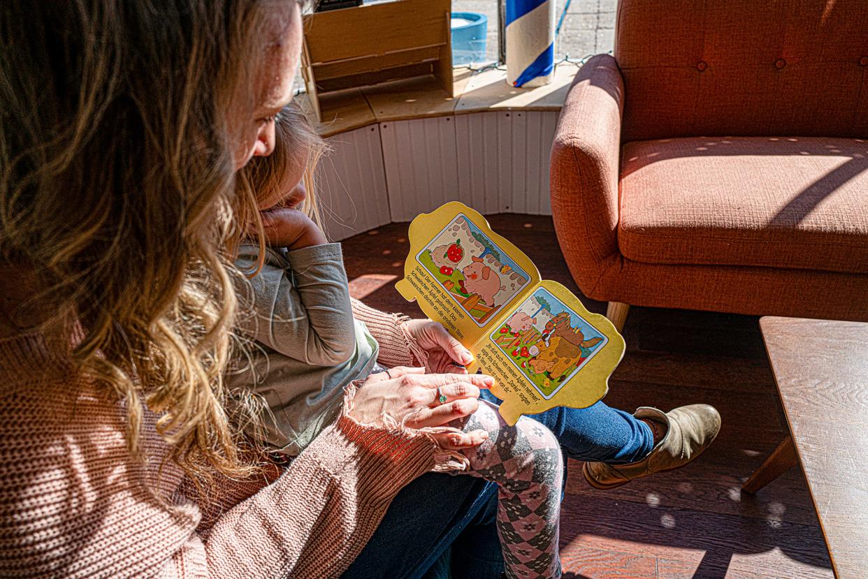 Angela Zeigerbacher reads a German book about a pig to her daughter Anja, 3, at A Novel Concept in downtown Lansing on Saturday, March 23, 2024.