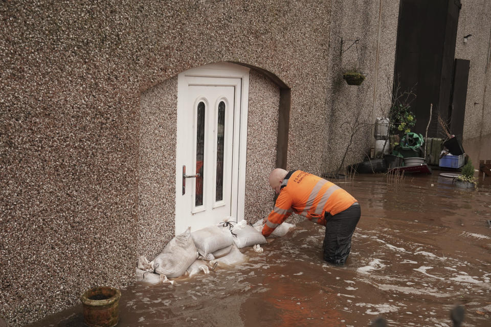 A view of a man piling sandbags outside a house, in Appleby-in-Westmorland, Cumbria, England, Sunday Feb. 9, 2020. Trains, flights and ferries have been cancelled and weather warnings issued across the United Kingdom as a storm with hurricane-force winds up to 80 mph (129 kph) batters the region. (Owen Humphreys/PA via AP)