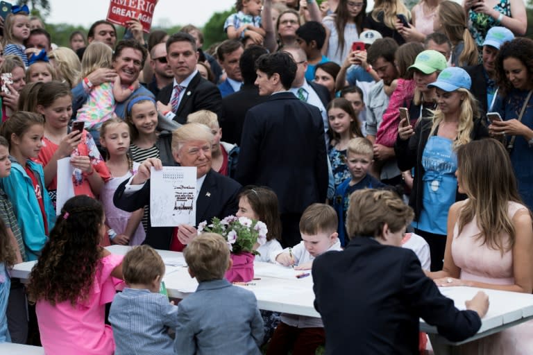 US President Donald Trump, Barron Trump (R) and First Lady Melania Trump join others to write notes to service members during the Easter Egg Roll on the South Lawn of the White House on April 17, 2017