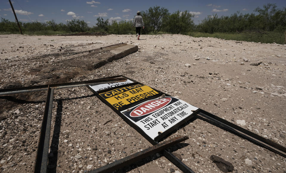 Ashley Williams Watt walks across the site of an abandoned well at her ranch, Friday, July 9, 2021, near Crane, Texas. Some of her wells are leaking chemicals such as benzene, a known carcinogen, into fields and drinking water. (AP Photo/Eric Gay)