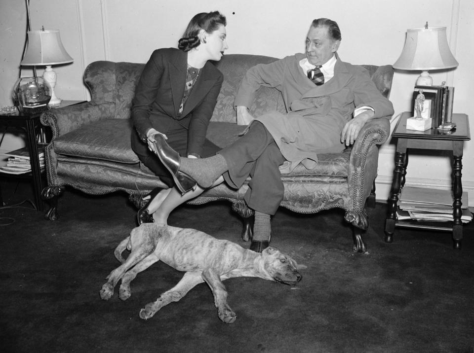 <p>Actress Elaine Barrie puts a slipper on the foot of her husband John Barrymore (grandfather of Drew Barrymore), as they lounge on the sofa with a dog by their side. </p>