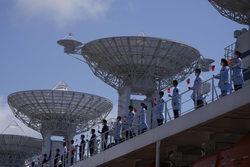 Crew of Chinese scientific research ship Yuan Wang 5 wave their country's national flags from the ship after arriving at Hambantota International Port in Hambantota, Sri Lanka, Tuesday, Aug. 16, 2022. The ship was originally set to arrive Aug. 11 but the port call was deferred due to apparent security concerns raised by India. (AP Photo/Eranga Jayawardena)