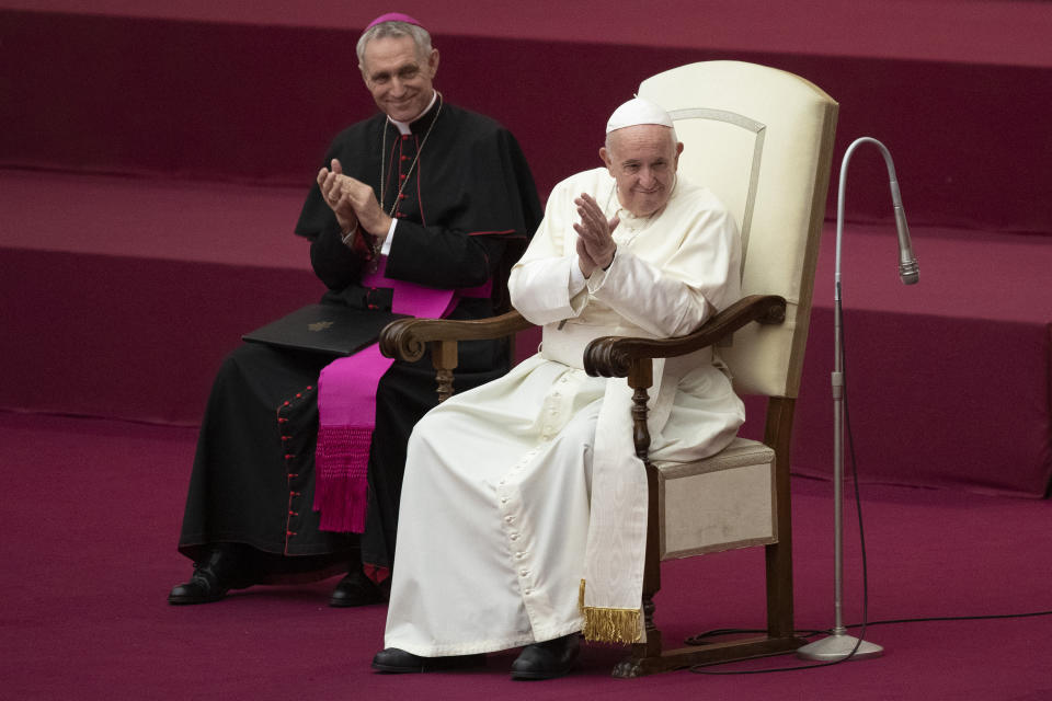 Pope Francis, flanked by Archbishop Georg Gaenswein, applauds in the Paul VI Hall at the Vatican during an audience with members of parish evangelization services, Monday, Nov. 18, 2019. (AP Photo/Alessandra Tarantino)