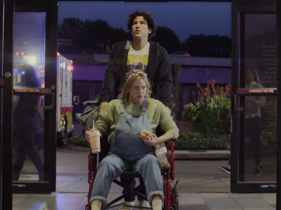 gabe pushing natalie in a wheelchair as she drinks a whataburger drink in look both ways