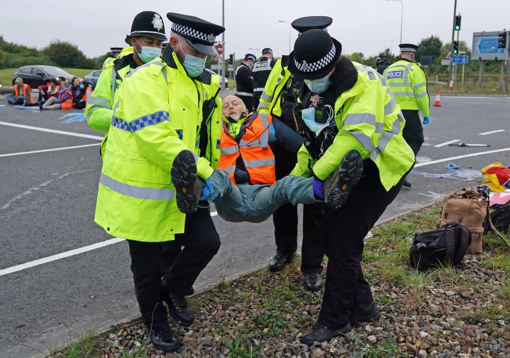 Police officers carry away an Insulate Britain  protester who had glued himself to the highway at a slip road at Junction 4 of the A1(M), near Hatfield (PA)