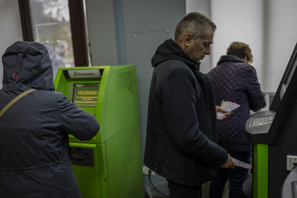 Residents operate ATMs inside a bank branch in Kherson, southern Ukraine, Monday, Nov. 21, 2022. (AP Photo/Bernat Armangue)