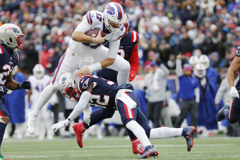 Buffalo Bills quarterback Josh Allen (17) leaps over New England Patriots free safety Devin McCourty (32) on a run during the first half of an NFL football game, Sunday, Dec. 26, 2021, in Foxborough, Mass. (AP Photo/Winslow Townson)