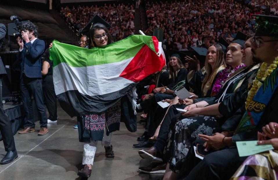Sacramento State student Mahrukh Jan Siddiqui, 31, holds up a Palestinian flag during the second Sacramento State commencement ceremony at Golden 1 Center on Friday.