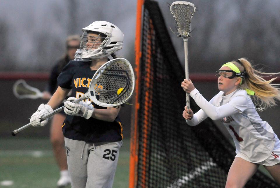 Victor goalie Kennedy Schottland, left, gets a pass away before Canandaigua's Hanna Davis can check the stick on Monday night.