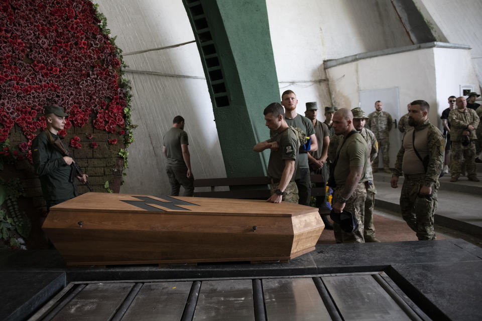 Soldiers of the Azov regiment pay their last respects to a serviceman killed in a battle against Russian troops in a city crematorium in Kyiv, Ukraine, Thursday, July 21, 2022. In the two months since Azovstal's defenders surrendered, ending their dogged defense of the massive plant that became a symbol of Ukrainian tenacity in the war against Russia, very few families and friends of those killed and captured have been able to begin the process of finding closure. (AP Photo/Andrew Kravchenko)